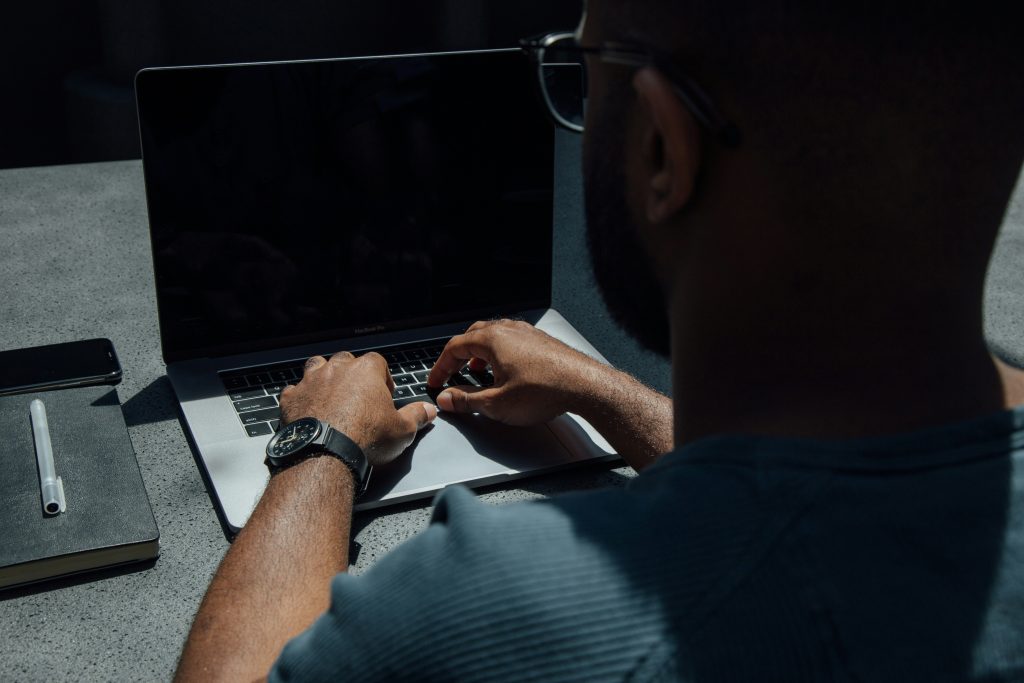 un bărbat stă în fața unui laptop. laptopul are ecranul stins. imaginea sugereaza tehnologia asistiva pentru persoanele cu dizabilitati