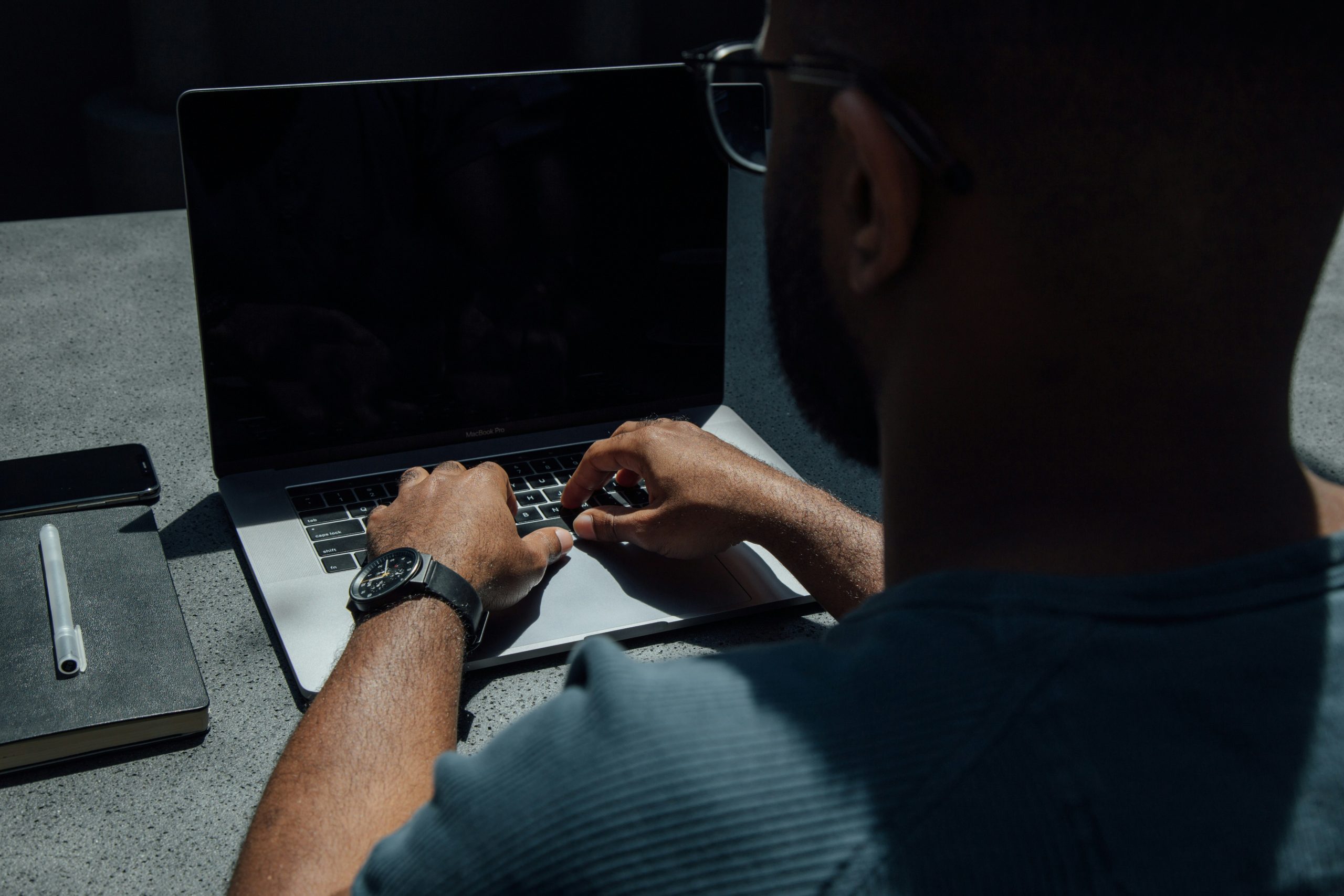 un bărbat stă în fața unui laptop. laptopul are ecranul stins. imaginea sugereaza tehnologia asistiva pentru persoanele cu dizabilitati